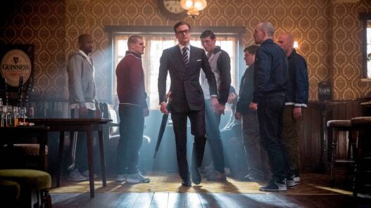 Escena de la película Kingsman: El servicio secreto, en la que se ve Colin Firth vestido de traje muy elegante entrando a un bar en el que hay chicos vestidos informales