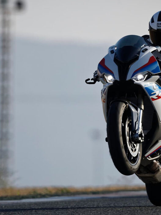 Motero haciendo un caballito con una moto deportiva en una carretera
