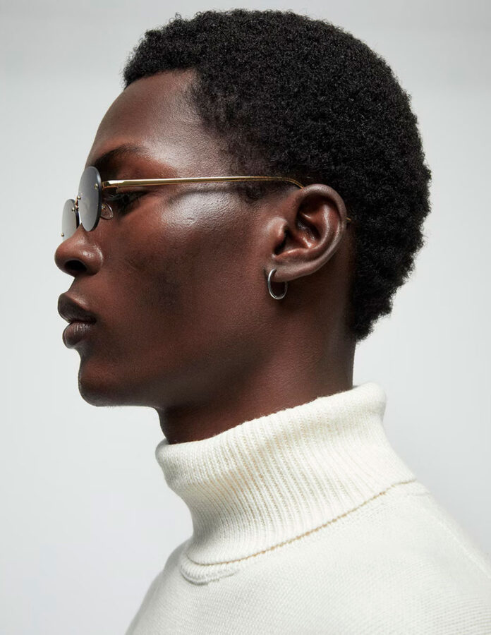Retrato de un modelo africano de perfil vistiendo un jersey de cuello alto y unas gafas de sol
