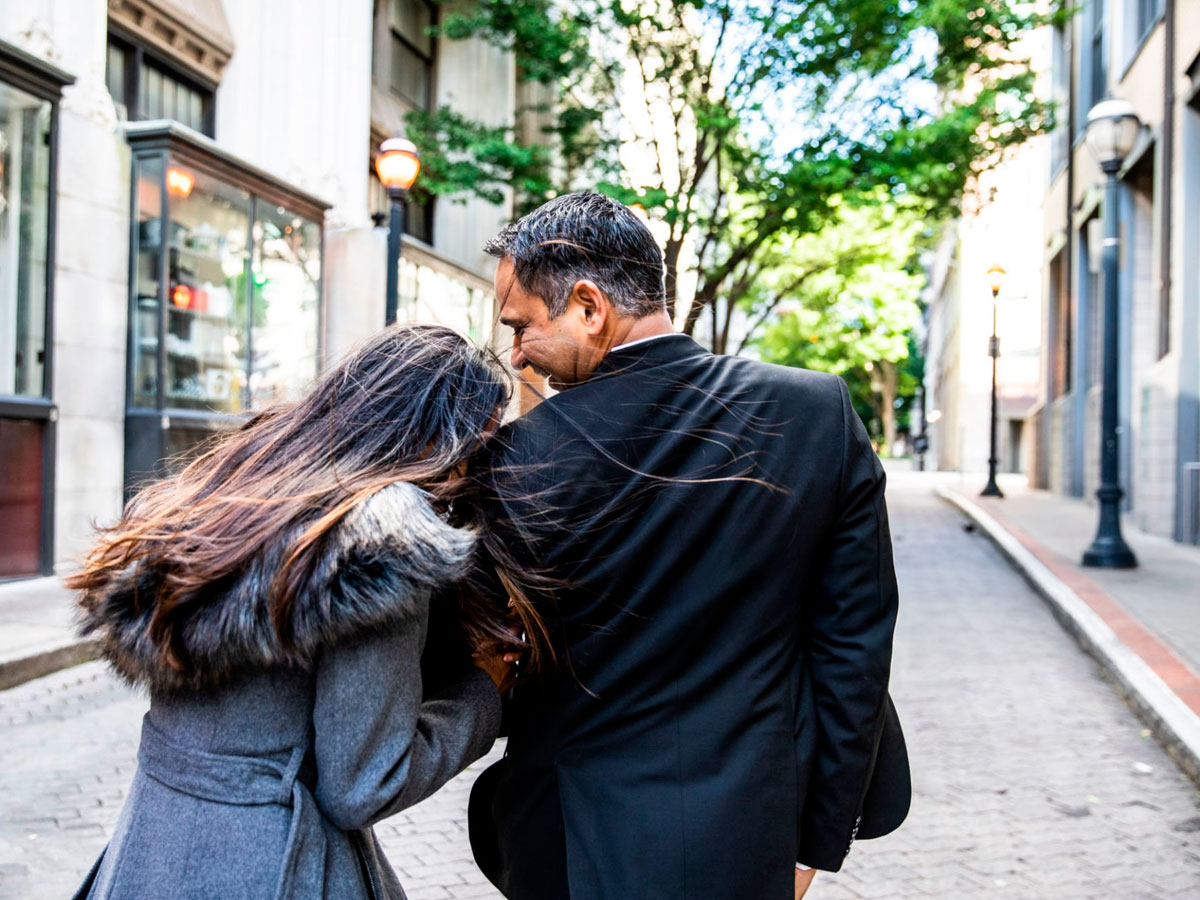 Pareja abrazada caminando por la calle vistos de espaldas