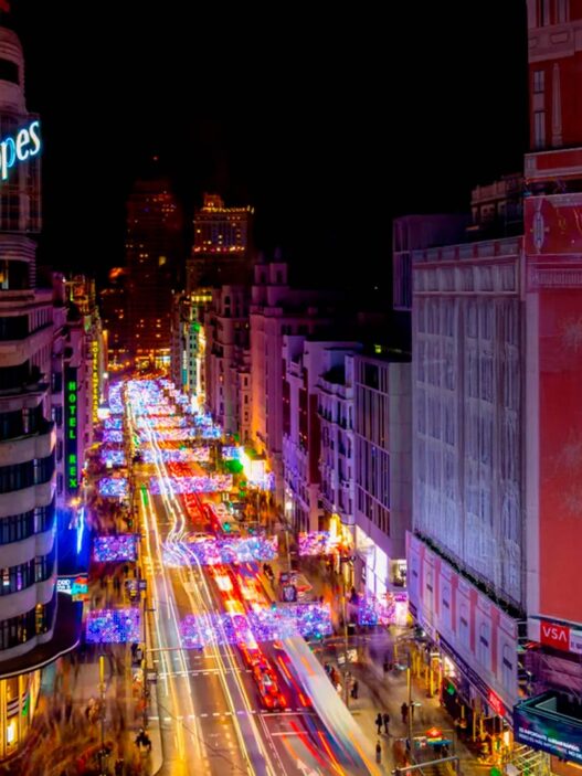 Vista aérea de la Gran Vía de Madrid de noche, con el edificio Schweppes en primer plano iluminado