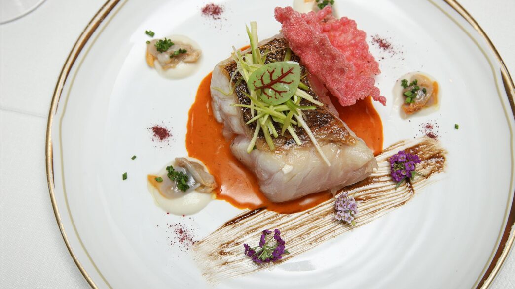 Plato de Suprema de mero con salsa de chiote, ajonegro, berberechos y crujiente de hibiscus del restaurante Zalacaín de Madrid