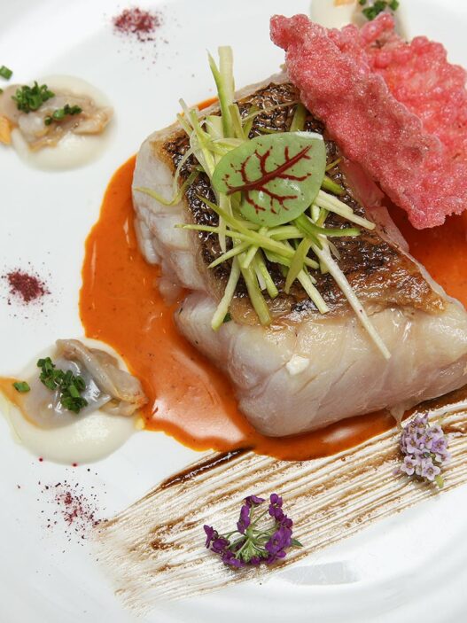 Plato de Suprema de mero con salsa de chiote, ajonegro, berberechos y crujiente de hibiscus del restaurante Zalacaín de Madrid