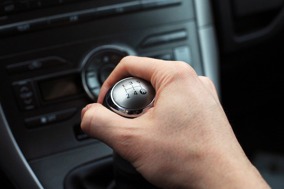 Mano accionando una palanca de cambios manual, gesto icónico de la conducción que muchos conductores echan de menos en los eléctricos