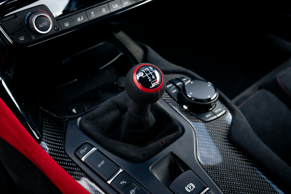 Palanca de cambios manual en el interior de un deportivo, símbolo de la conducción tradicional que los coches eléctricos buscan recuperar