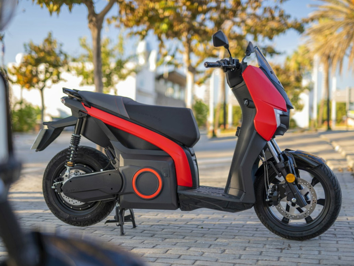 SEAT MÓ 125 en color rojo estacionado en una avenida con palmeras.