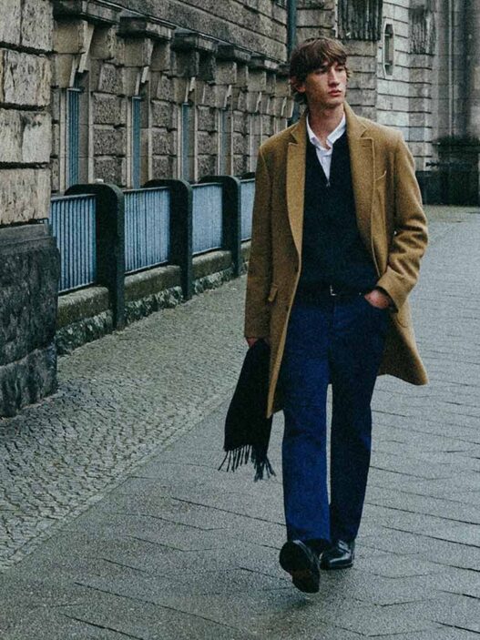 Modelo caminando por la calle con un abrigo de lana largo color camel y un look para el día a día.