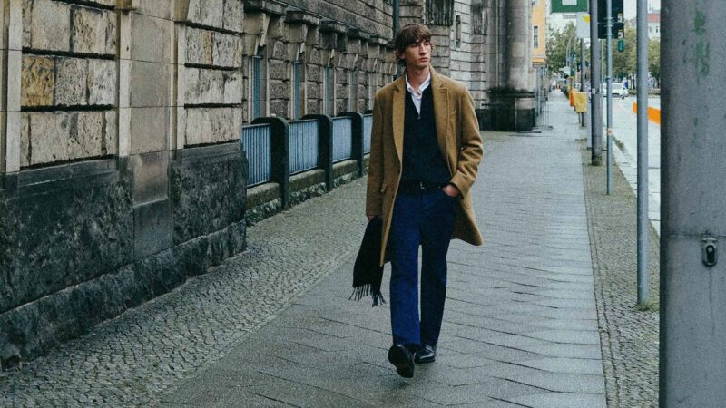 Modelo caminando por la calle con un abrigo de lana largo color camel y un look para el día a día.