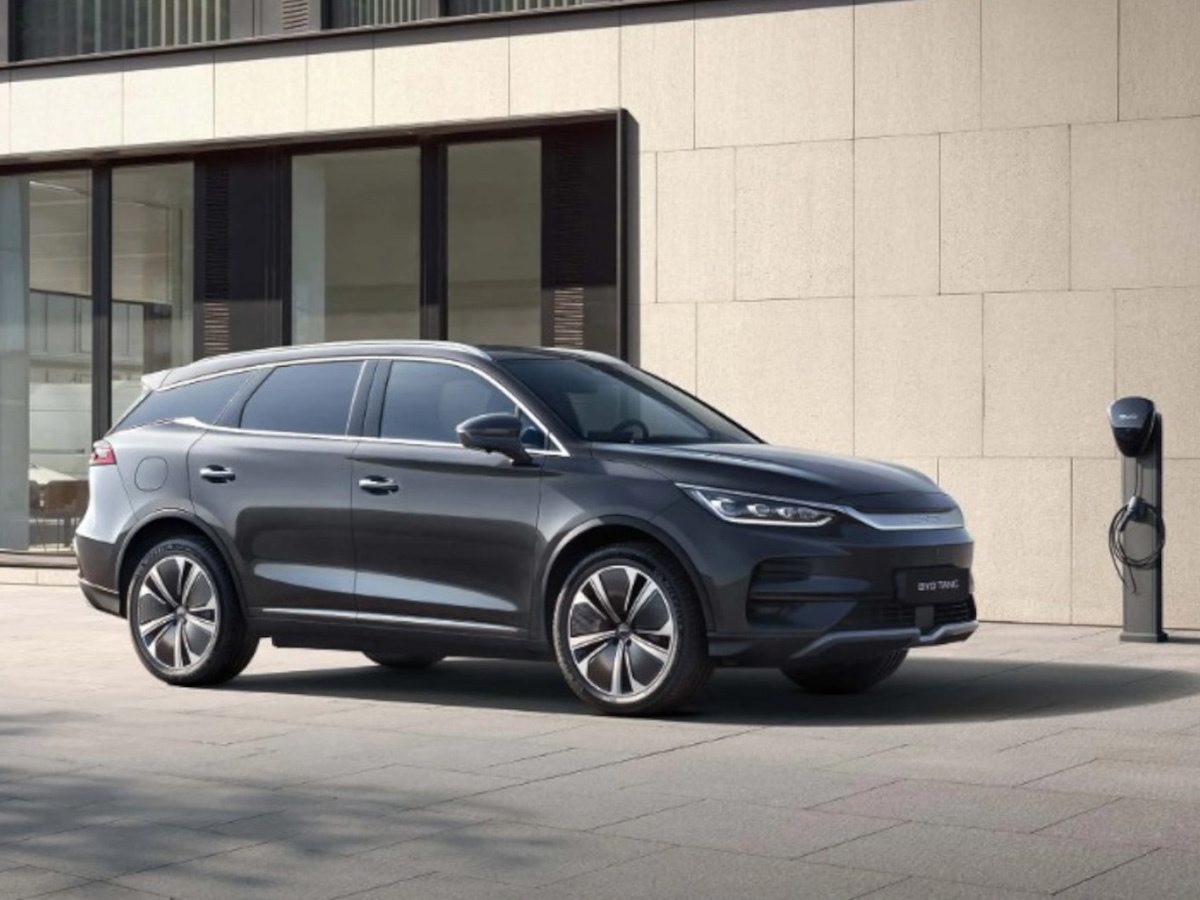 BYD Tang aparcado fuera de una casa con el cargador en la pared de la casa