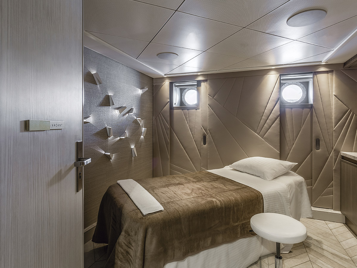 Sala de masajes del spa del crucero Debussy con camilla y luz cálida