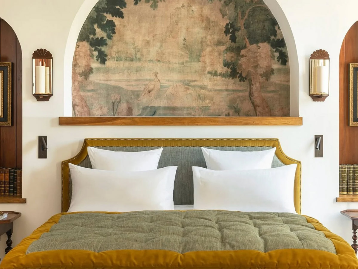 Suite del hotel Airelles Palladio Venezia, en la que se ve una cama de matrimonio con una colcha verde oliva muy elegante con un bordado dorado.
