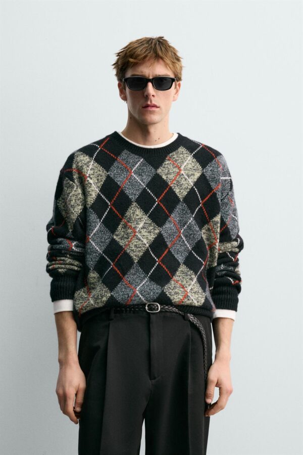 Hombre con jersey de rombos de cashmere en tonos grises, negros y rojos de la colección Aaron Levine x Zara