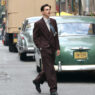 El actor Timothée Chalamet en una escena de la película Marty Supreme andando por la calle con un traje cruzado