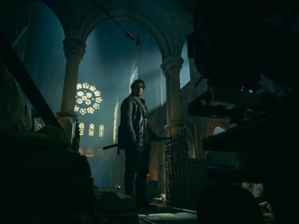 Henry Cavill vestido de negro como Connor MaCleod en una iglesia gótica en el remake de Los Inmortales.
