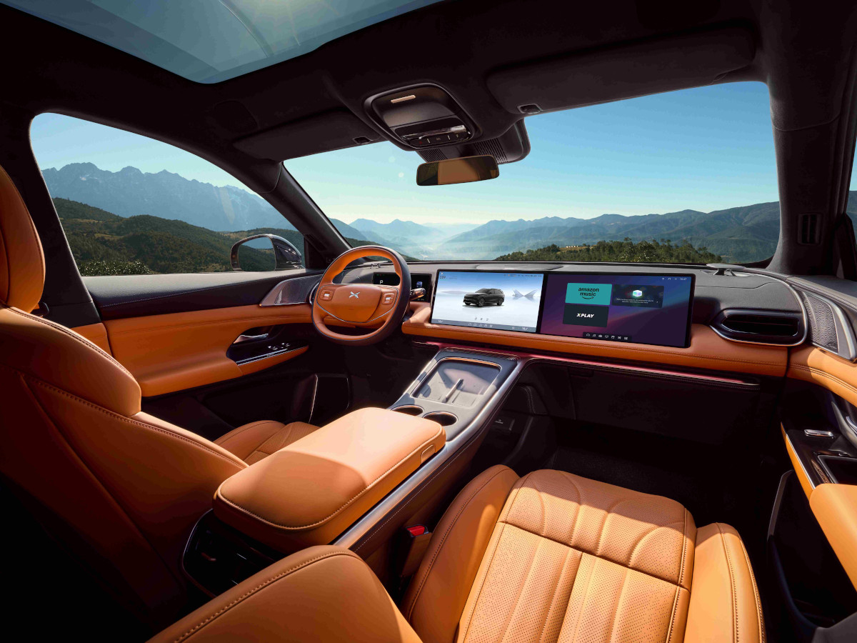 Interior del coche XPeng G6, muy elegante, con los asientos tapizados en piel color naranja y dos pantallas en la parte delantera.