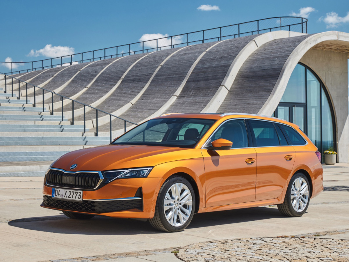 Interior del Skoda Octavia con volante a la izquierda, salpicadero en tonos negros y marrones, pantalla central táctil grande con navegación activa y asientos delanteros tapizados en cuero.