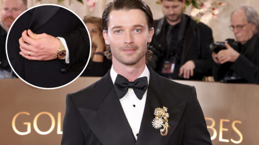 El actor Patrick Schwarzenegger posando en la alfombra roja de los Globos de Oro 2026 con un reloj Omega y vestido de Dolce & Gabbana.