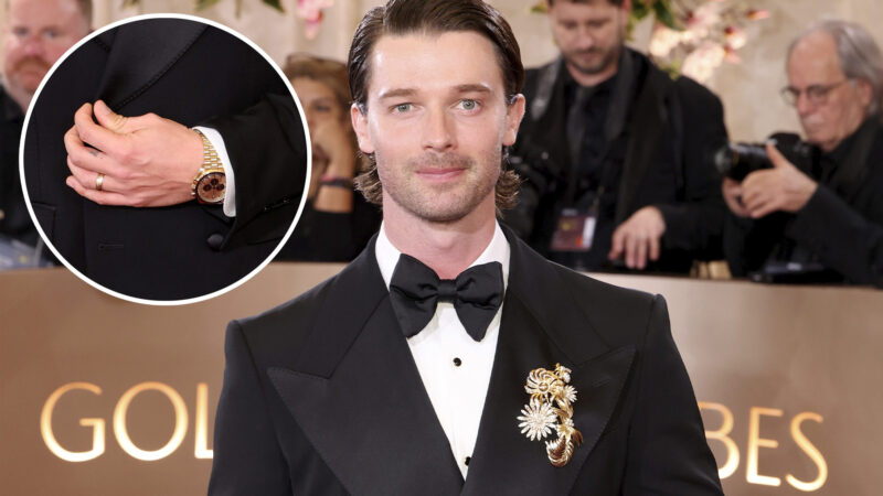 El actor Patrick Schwarzenegger posando en la alfombra roja de los Globos de Oro 2026 con un reloj Omega y vestido de Dolce & Gabbana.