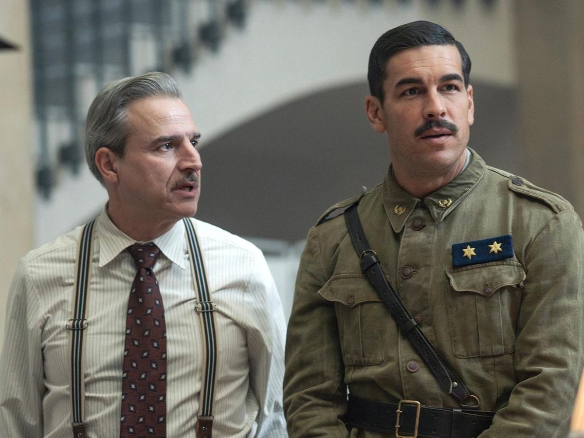 Alberto San Juan con camisa blanca, tirantes y corbata y a su lado Mario Casas vestido de militar en la película La cena.