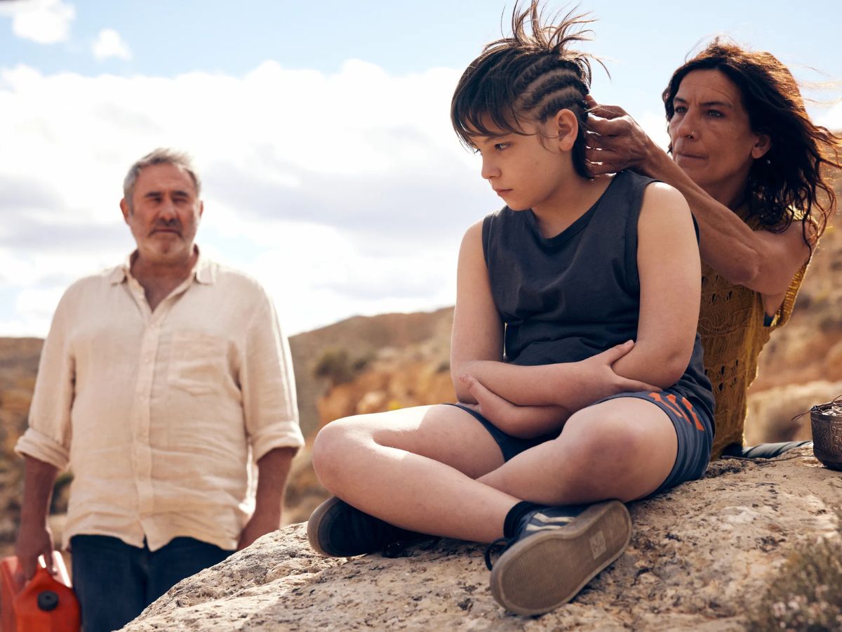 Una chica haciendo trenzas a un niño en el desierto en una escena de la película Sira.