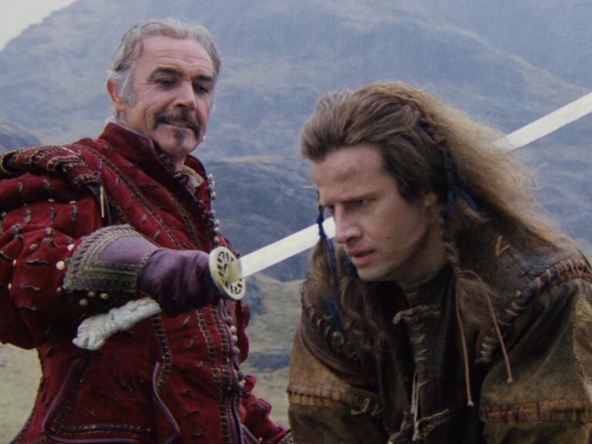 Sean Connery con un traje rojo apuntando con una espada a Christopher Lambert con el pelo largo y un abrigo marrón en la película Los Inmortales.