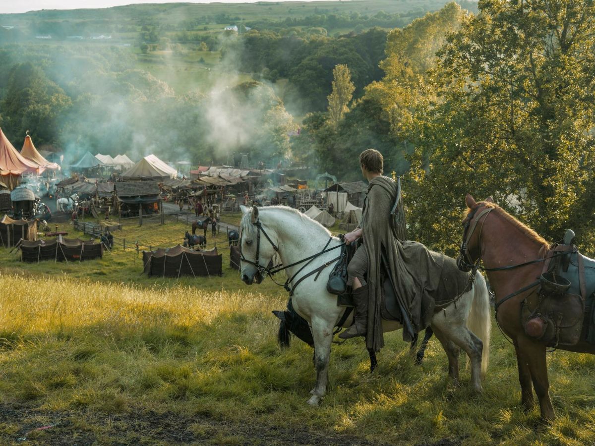 Ser Duncan el alto montando a caballo en un paisaje verde con tiendas de campaña en un pueblo de Poniente en El caballero de los siete reinos.