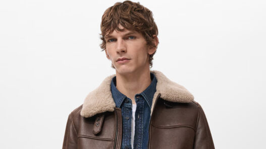 Modelo joven, de unos 25 años vestido con una cazadora color marrón con cuello e interior de borreguito. La cazadora es de Mango