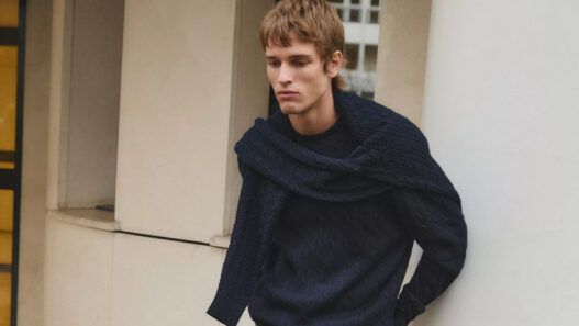 Modelo Jeray Allgayer vestido con un jersey de punto azul marino y otro jersey sobre los hombros.