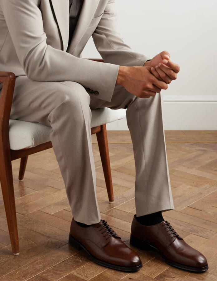 hombre vestido con un traje gris tostado y con unos zapatos de vestir modelo derby en color marrón