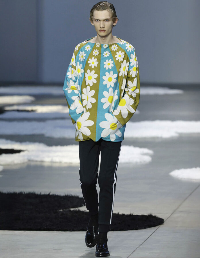 Modelo del desfile de Prada desfilando en la pasarela con un look con estampado de flores.