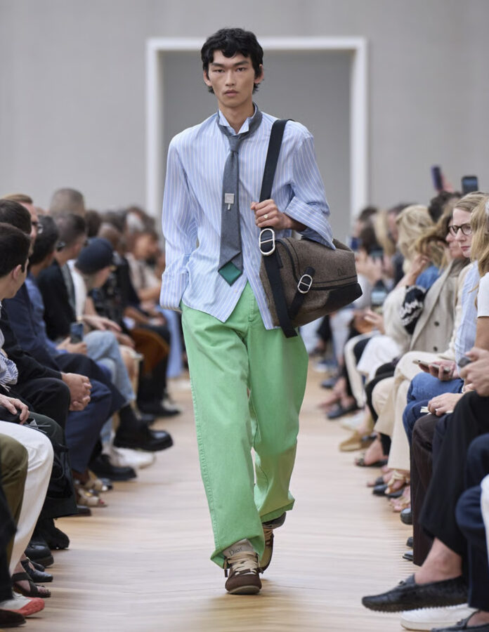 modelo de la firma Dior Homme durante el desfile de la temporada primavera/verano 2026 vistiendo la tendencia de camisas a rayas con corbata