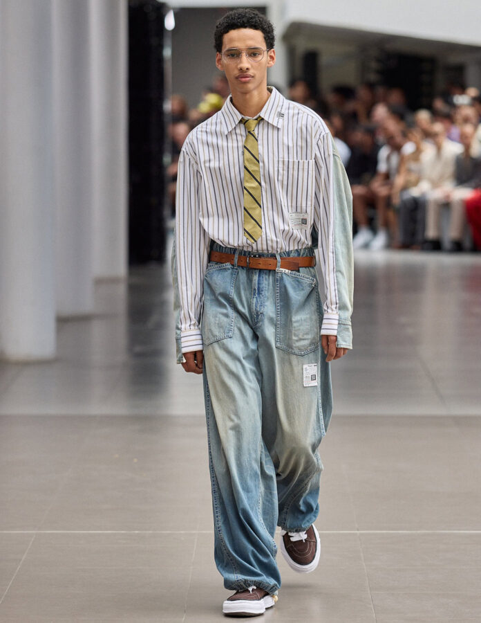 modelo de la firma Maison Mihara durante el desfile de la temporada primavera/verano 2026 vistiendo la tendencia de camisas a rayas con corbata