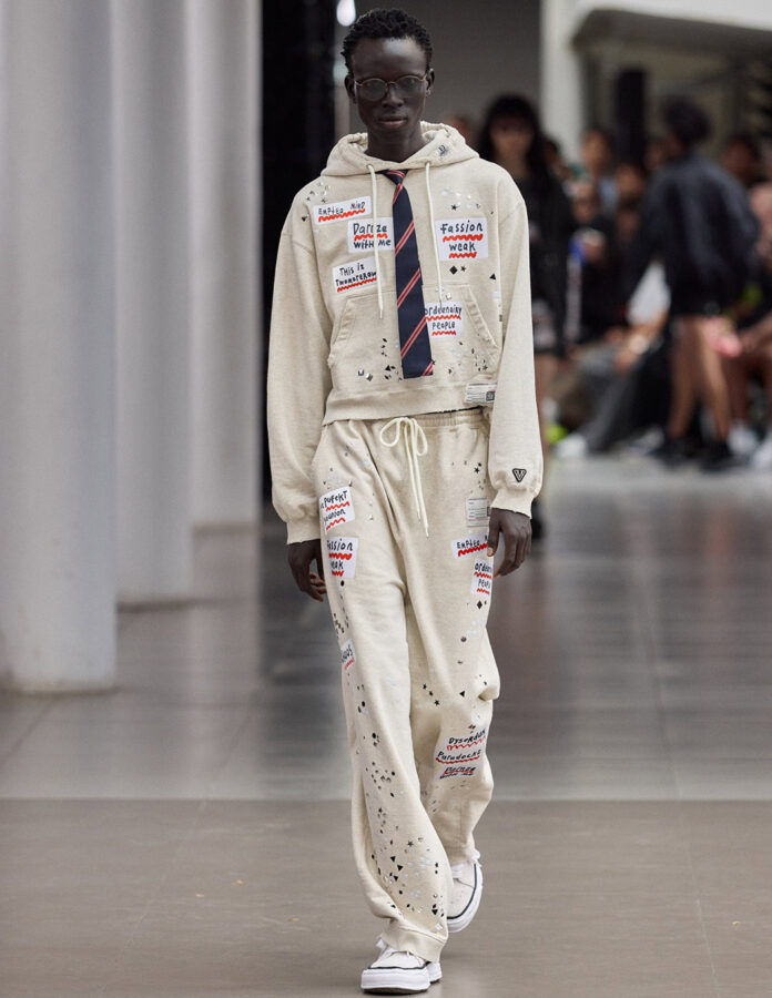 modelo del desfile Maison Mihara Yasuhiro temporada primavera/verano 2026 desfilando con un pantalón de chándal combinado con prendas más elegantes.