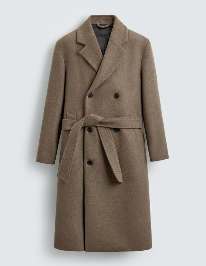 Abrigo largo camel para hombre, de corte cruzado y con cinturón, fotografiado sin modelo, con solapas de muesca, botones negros y largo por debajo de la rodilla.