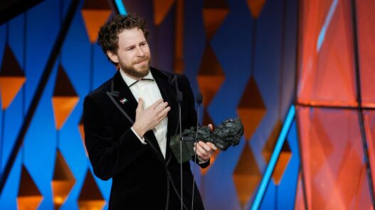 Álvaro Cervantes vestido con traje negro y camisa blanca sujetando el Goya que ha ganado como Mejor Actor de reparto por Sorda.