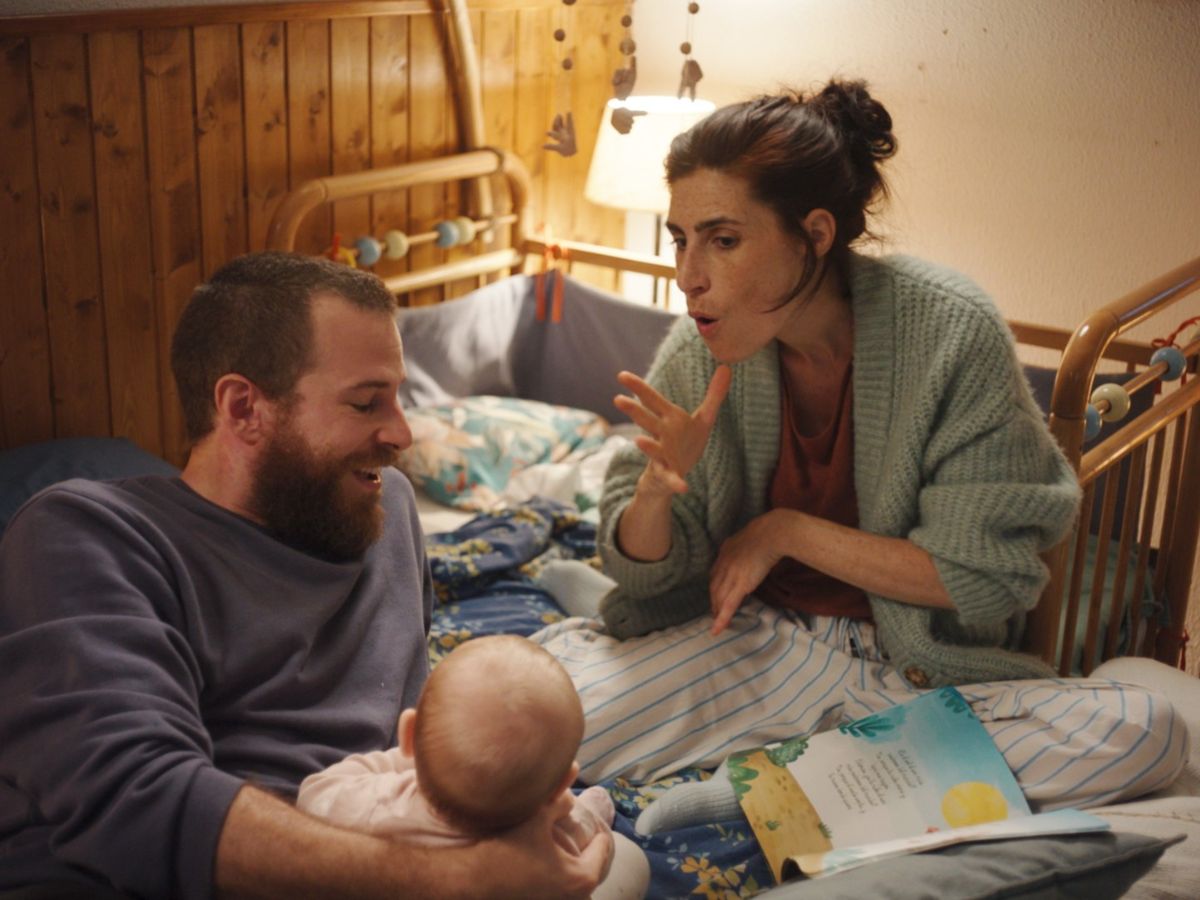 Álvaro Cervantes tumbado en la cama junto a la actriz Miriam Garlo y un bebé en la película Sorda.