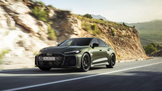 Audi RS 5 PHEV en color verde circulando por carretera de montaña, vista delantera tres cuartos