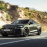 Audi RS 5 PHEV en color verde circulando por carretera de montaña, vista delantera tres cuartos