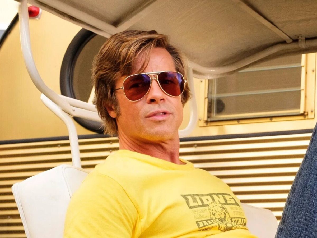 Primer plano de Brad Pitt con camiseta de manga corta amarilla y gafas de sol interpretando a Cliff Booth en Érase una vez en... Hollywood.