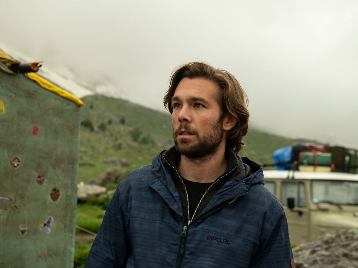 Carlos Cuevas con una chaqueta azul y una montaña de fondo en una escena de la película La Fiera.