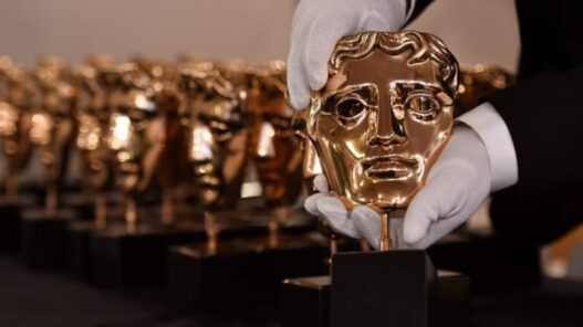 Unas manos con guantes blancos sujetando un Premio BAFTA fabricado en bronce fosforoso.