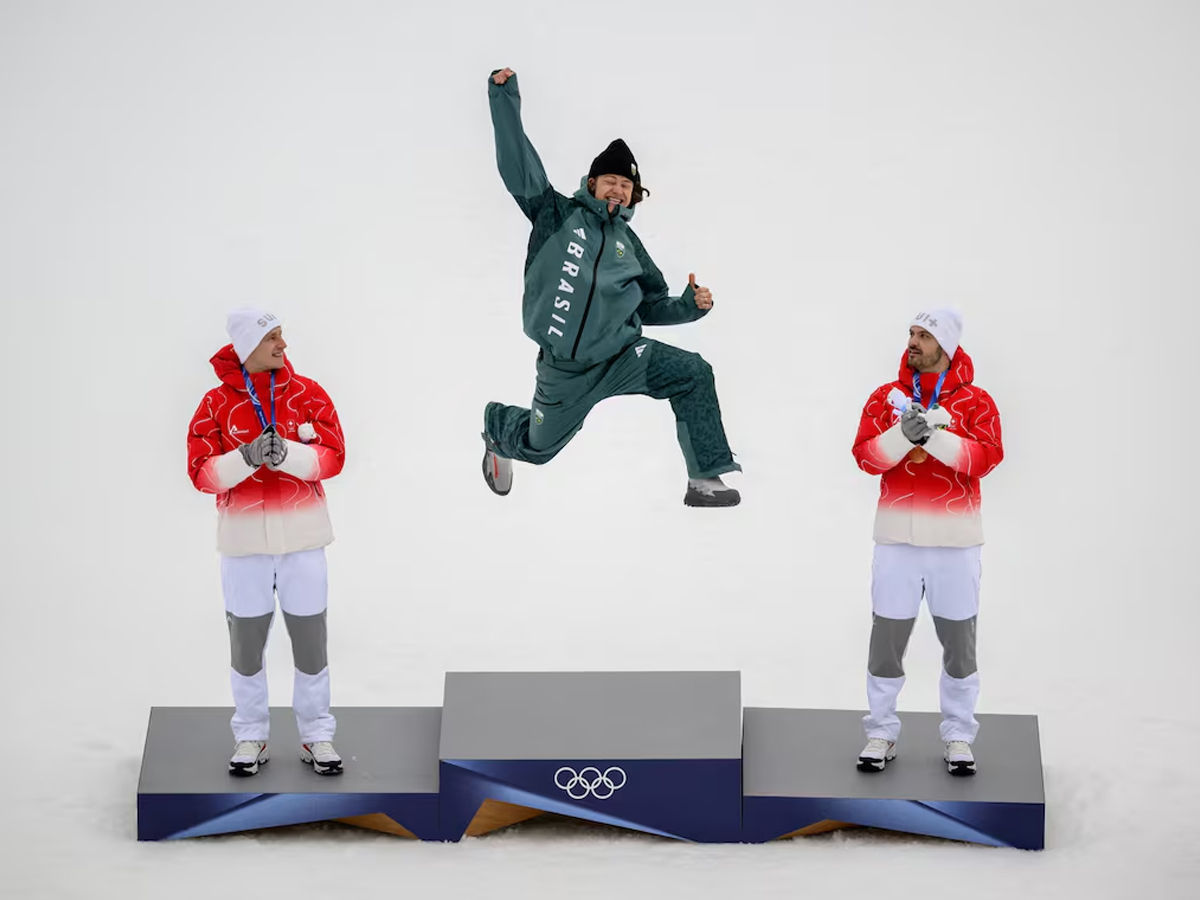 Lucas Pinheiro Braathen salta en el podio acompañado por el medallista de plata suizo Marco Odermatt y el medallista de bronce suizo Loic Meillard durante el podio del evento de esquí alpino de slalom.