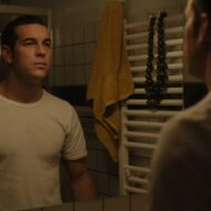 Premios Goya: Las cinco actuaciones masculinas que han marcado el cine español en 2026 Mario Casas mirándose al espejo con una camiseta de manga corta blanca en una escena de la película Muy Lejos.