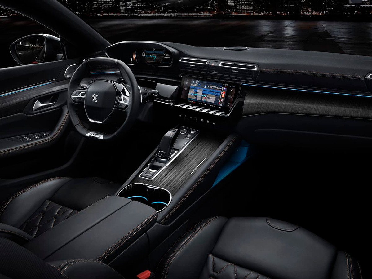 Interior de un Peugeot 508 visto desde la plaza del acompañante, con volante compacto, pantalla central táctil, mandos tipo piano y consola central elevada.