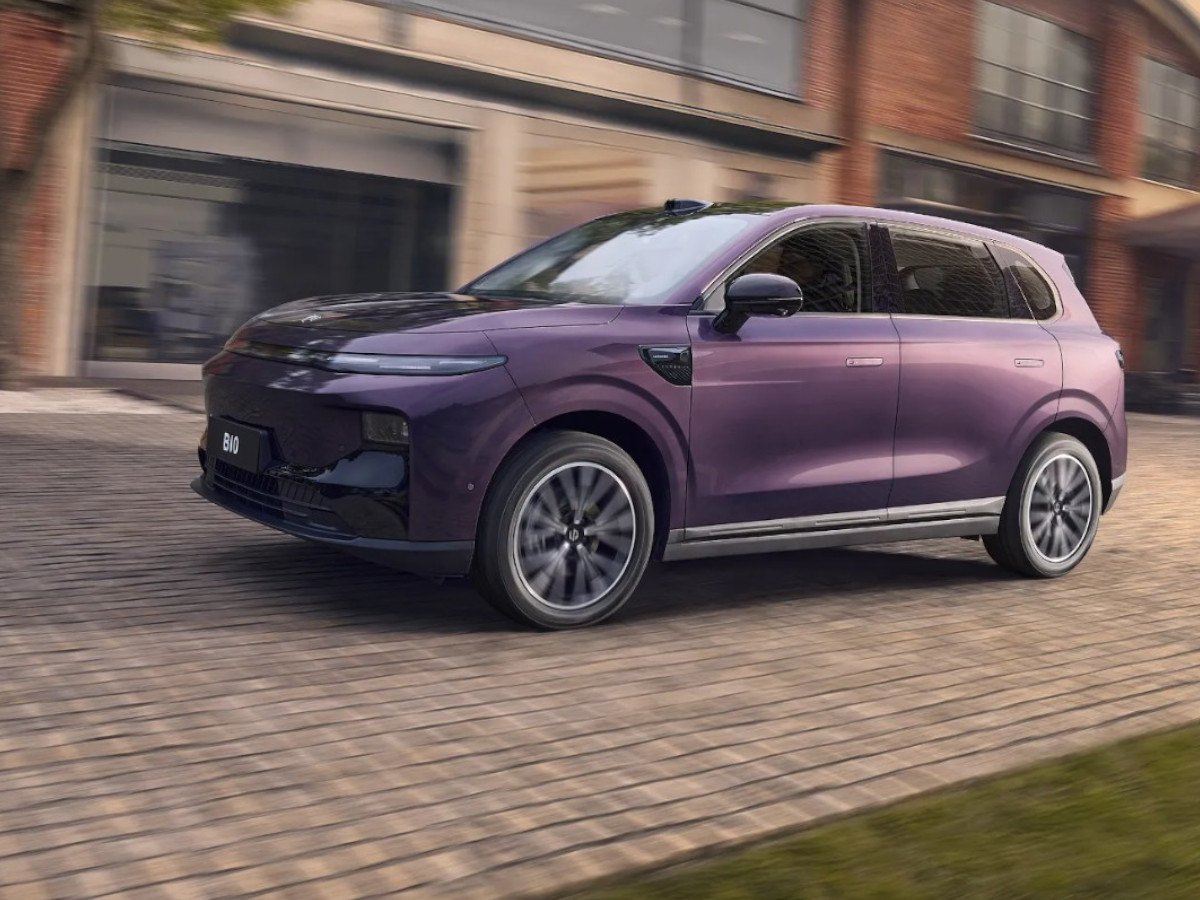 SUV eléctrico Leapmotor B10 de color morado circulando por una calle urbana, visto en perfil lateral, con edificios de ladrillo desenfocados al fondo.