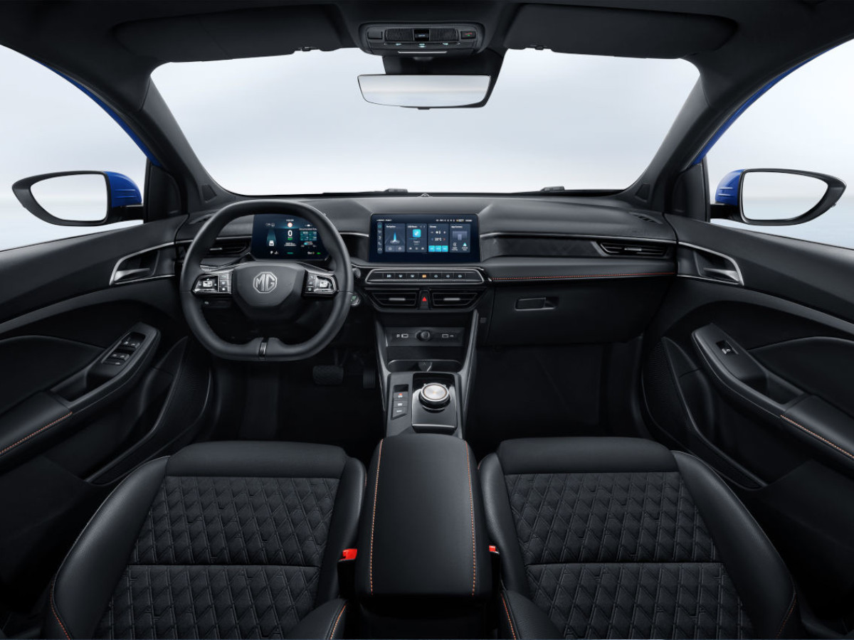 Interior del MG3 Hybrid+ visto desde la parte trasera, con salpicadero negro, volante multifunción con logotipo MG y pantalla central digital encendida.