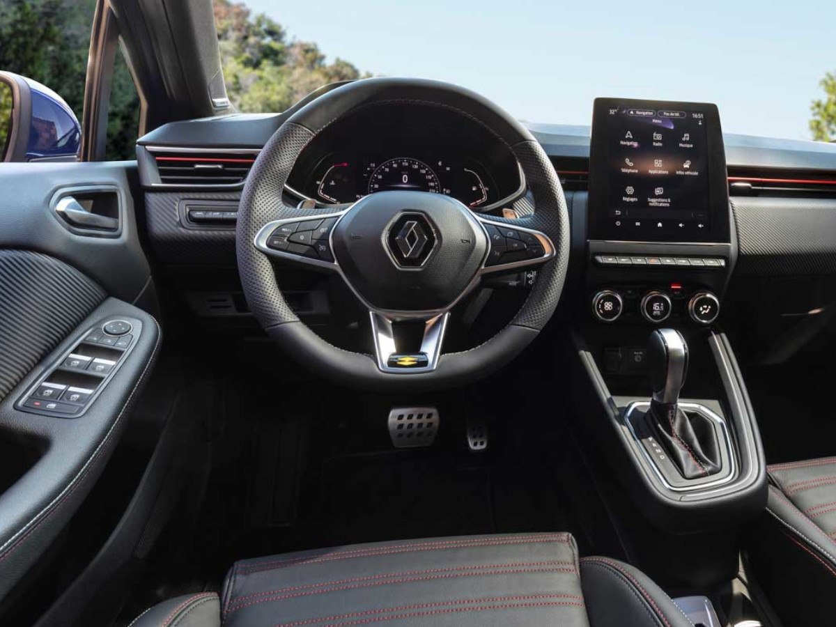 Interior del Renault Clio E-Tech visto desde el asiento del conductor, con volante multifunción, instrumentación digital y pantalla central vertical encendida.