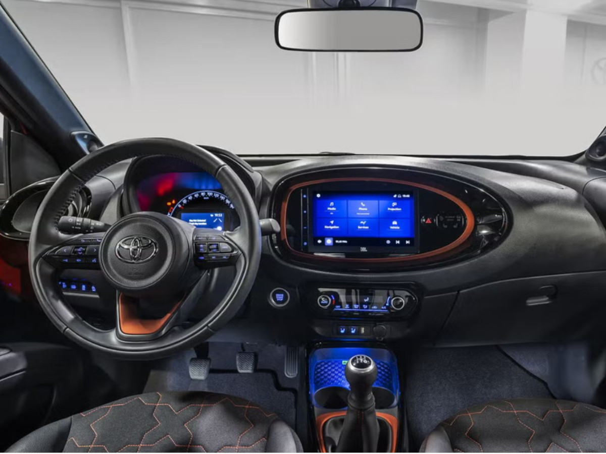 Interior del Toyota Aygo X Cross visto desde el asiento del conductor, con volante multifunción, cuadro de instrumentos digital y pantalla central integrada en el salpicadero.