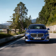 Los mejores coches que puedes comprar en 2026 por hasta 40.000 euros BMW Serie 2 Active Tourer de color azul visto de frente circulando por una carretera de montaña junto a un lago, con árboles y un muro de piedra a los lados.