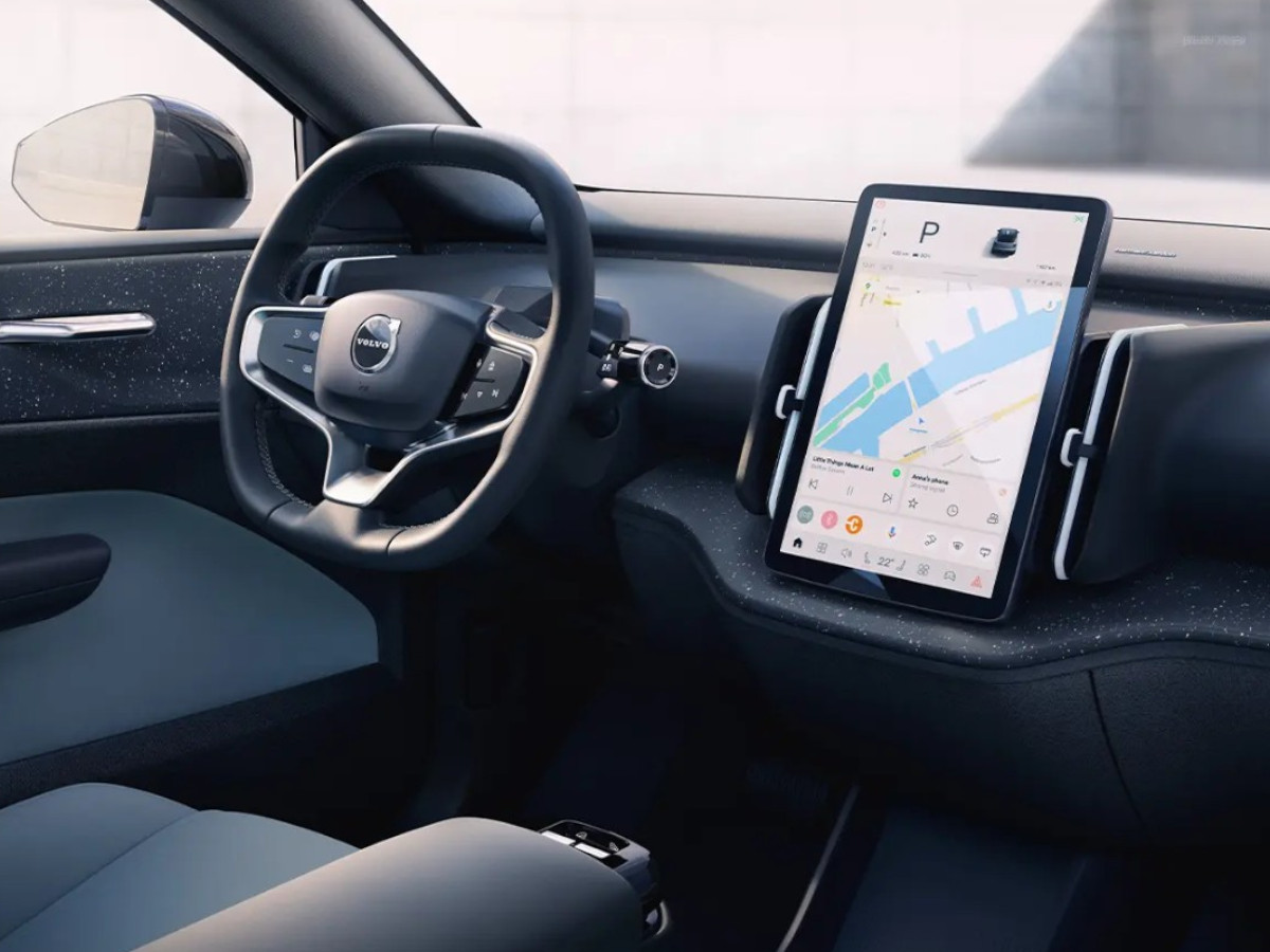Interior del Volvo EX30 con volante Volvo, pantalla táctil central en posición vertical y salpicadero de diseño minimalista en tonos oscuros.